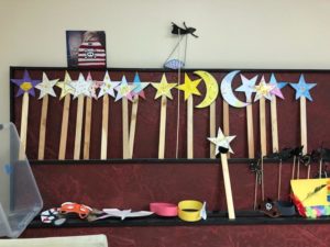A group of sticks stand in a row. Each stick has a star or crescent moon attached to the top