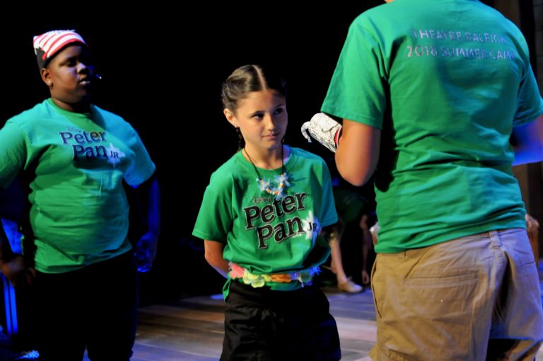 A young girl in a green shirt is eyeing a taller boy wearing a hook