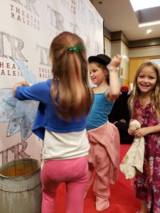 A group of children play with photo booth props in a lobby.