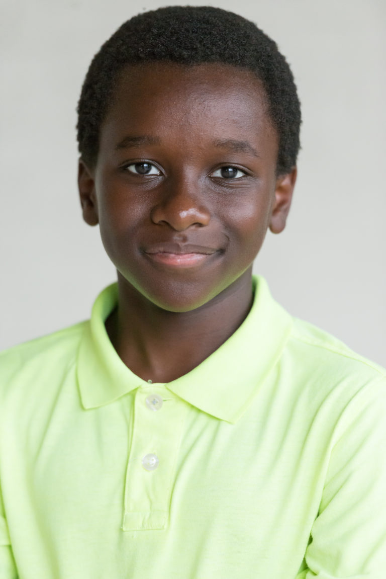 A young boy with dark skin wearing a green shirt